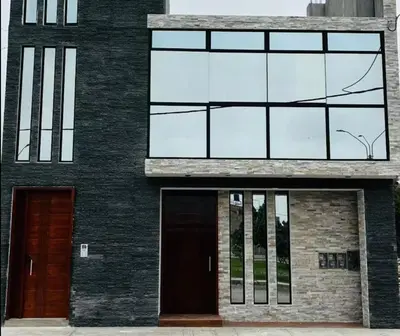a black building with glass windows and a door at Apartamentos como en casa in Chancay