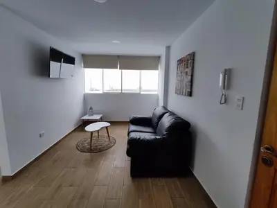 a living room with a black couch and a table at Departamento de playa in Lima