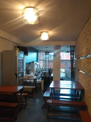 a restaurant with wooden tables and a room with a kitchen at La Casa de mi Abuelo in Cusco