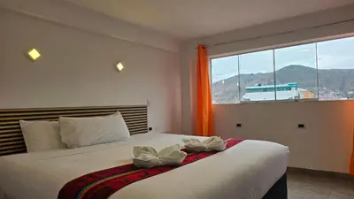 a bedroom with a bed and a large window at Hotel Cusco Museo in Cusco