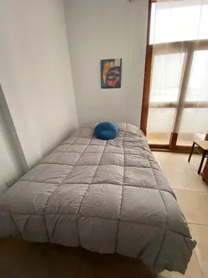 a bed in a bedroom with a blue pillow on it at Hostal Lobitos in Cerro Azul