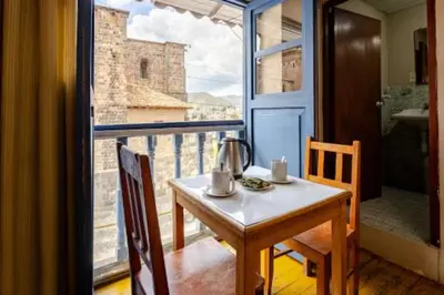 a table and chairs in a room with a window at Vista al Qoricancha - 2 cuadras de la Plaza in Cusco