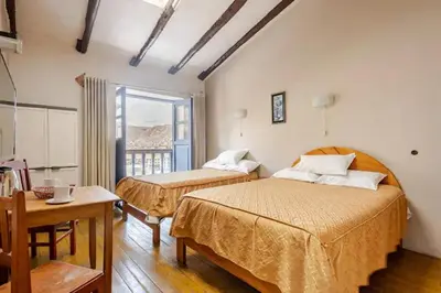 a bedroom with two beds and a table and a window at Vista Qoricancha - 2 cuadras Plaza Principal in Cusco