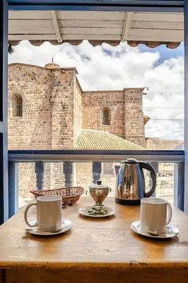 a table with two cups and a tea kettle on a window at Vista Qoricancha - 2 cuadras Plaza Principal in Cusco