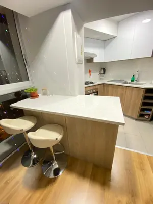a kitchen with a white counter and two stools at Vista piso 24 in Lima