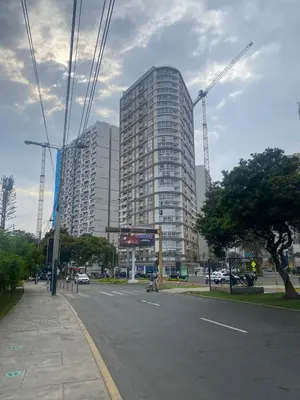 a city street with a tall building with cranes at Vista piso 24 in Lima