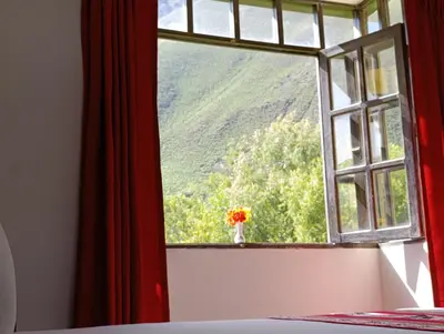 a window with a vase of flowers in a room at Samana House Ollantaytambo in Ollantaytambo