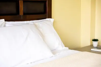 a bed with white pillows on top of it at San Miguel Awanka Hotel in Lima