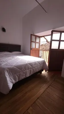 a bedroom with a bed and a large window at Antuquita's House in Cusco