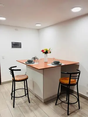 a kitchen with two stools and a counter with flowers at MONTERRICO POLO APARTS #8 - Dpto de 2 camas Frente Embajada de USA con AC in Lima