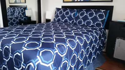 a bed with a blue and white comforter at Temporal Apartment in Lima