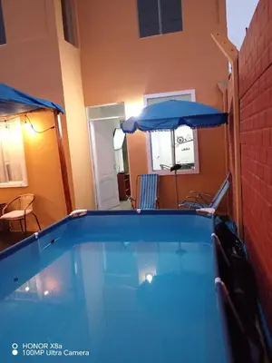 a swimming pool with an umbrella next to a house at Sweet Rustic Home in Hacienda Santo Domingo