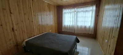 a bedroom with a bed in a wooden room with a window at Cabañas de casa hospedaje Mirador l in Oxapampa