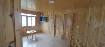 a room with wooden walls and a table and a window at Cabañas de casa hospedaje Mirador l in Oxapampa