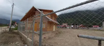 a small wooden house behind a chain link fence at Cabañas de casa hospedaje Mirador l in Oxapampa