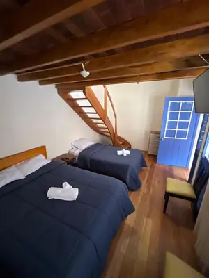 a bedroom with two beds and a chair and a window at Departamento 1 Waynapata Centro Histórico de Cusco in Cusco
