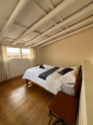 a bedroom with a bed and a table in it at Departamento 1 Waynapata Centro Histórico de Cusco in Cusco