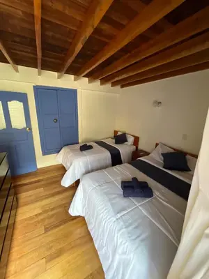 three beds in a room with blue doors and wooden floors at Departamento 1 Waynapata Centro Histórico de Cusco in Cusco