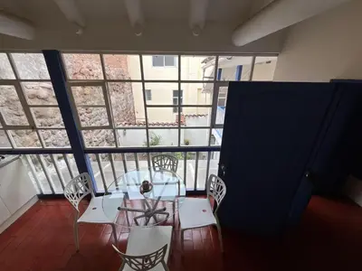 a table and chairs in a room with a large window at Departamento 1 Waynapata Centro Histórico de Cusco in Cusco