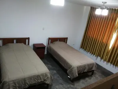 a bedroom with two beds and a window with curtains at Casa Extremadura in Lima