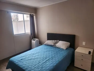 a bedroom with a bed with a blue comforter and a window at Apartamento en Lima in Lima