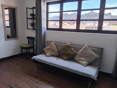 a couch with pillows sitting in a room with a window at Apartment in the historic center of Cusco in Cusco