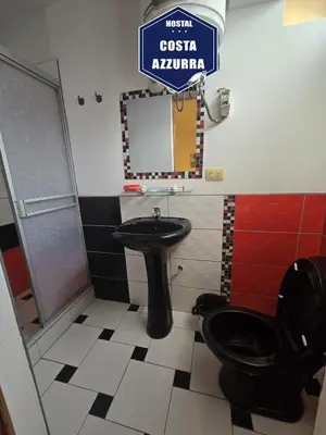 a bathroom with a toilet and a sink and a mirror at Hostal COSTA AZZURRA in Cerro Azul