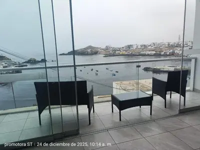 a balcony with chairs and a table and a view of a harbor at Mirador sur in San Bartolo