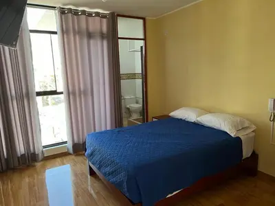 a bedroom with a blue bed and a bathroom at HOTEL SAMANAHUASi in Nazca