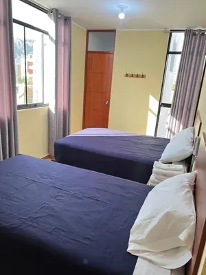 a bedroom with two beds and a window at HOTEL SAMANAHUASi in Nazca