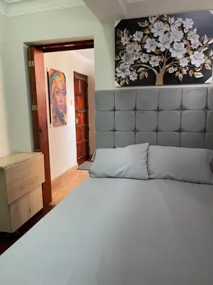 a bedroom with a large bed and a painting on the wall at Mini Apartment ARES in Lima