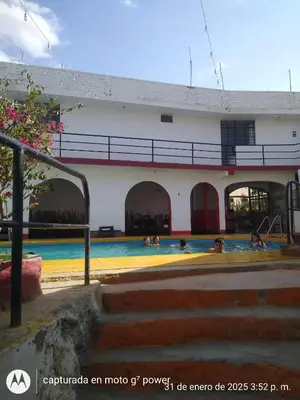 a building with people swimming in a swimming pool at Hospedaje snack bar titanic in Ica