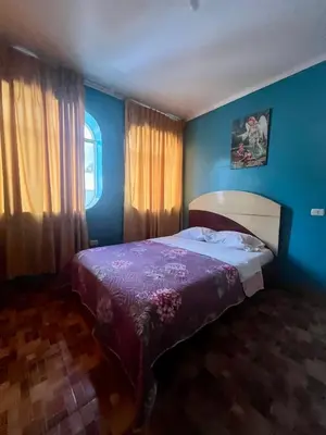 a bedroom with blue walls and a bed with a purple bedspread at Hostal Wassiki in Huánuco
