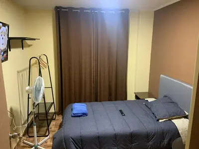 a bedroom with a blue bed and a fan at Family Home Furnished Centro Chincha Alta in Chincha Alta