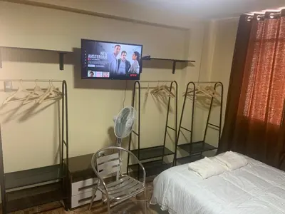 a bedroom with a bed and a tv on the wall at Family Home Furnished Centro Chincha Alta in Chincha Alta