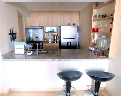 a kitchen with a counter and two stools in it at Departamento Playa Arica - Lurín in Lurín