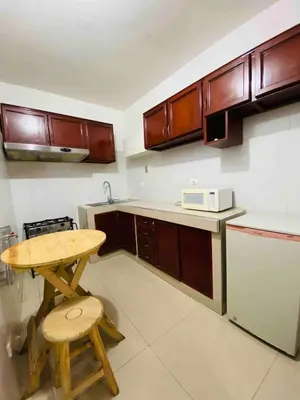 a kitchen with wooden cabinets and a wooden table and stool at Minidepartamento La Molina Junin 1 in Lima