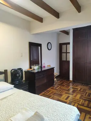 a bedroom with a bed and a dresser and a clock at Amplia habitación independiente con baño privado in Lima