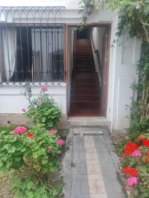 a staircase leading to a house with pink flowers at Amplia habitación independiente con baño privado in Lima
