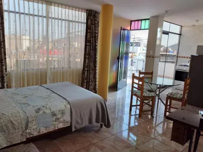 a bedroom with a bed and a table and a balcony at Nice stay in Los Olivos in Lima