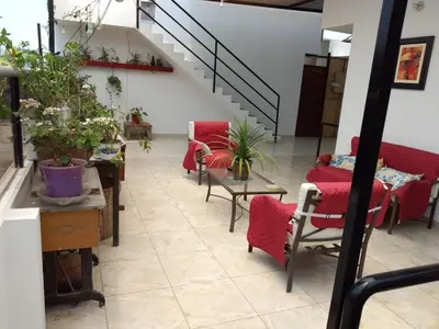 a living room with red chairs and a staircase at Comfortable stay in Los Olivos in Lima