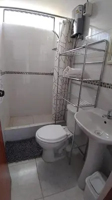 a white bathroom with a toilet and a sink at Comfortable stay in Los Olivos in Lima