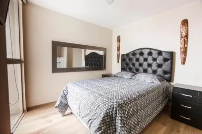 a bedroom with a black bed and a mirror at Vista piloto cerca Miraflores y Centro Histórico, seguridad 24 h in Lima
