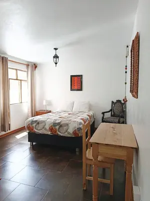 a bedroom with a bed and a wooden table at Casa Munayki in Ayacucho