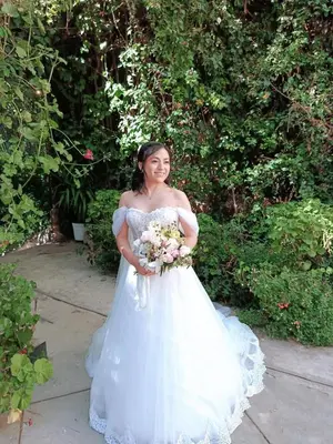 a woman in a white dress holding a bouquet of flowers at Casa Munayki in Ayacucho