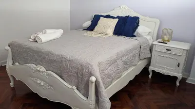 a white bed with blue pillows and a night stand at Mini depa en el corazón de Miraflores in Lima