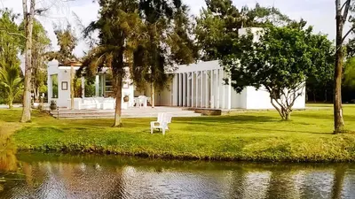 a white chair sitting in front of a house at Casa de Campo con lago en Mala in Mala