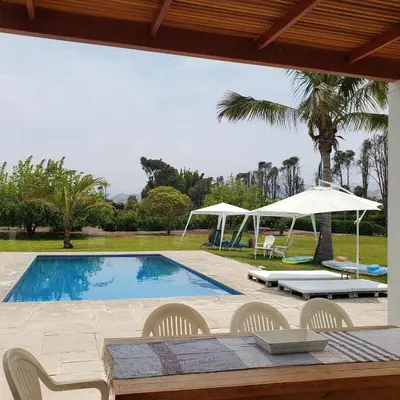 a swimming pool with chairs and a table and an umbrella at Casa de Campo con lago en Mala in Mala