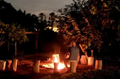 a man standing in front of a fire at night at Casa de Campo con lago en Mala in Mala