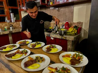 a man standing in front of a table with plates of food at Waranway Lodge Huayopata in Quillabamba